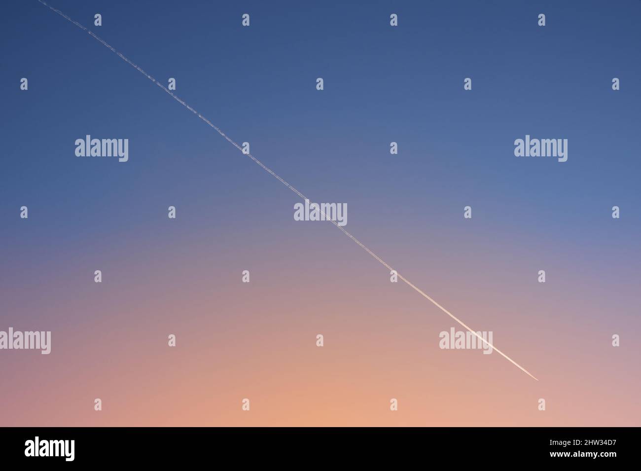 Velivolo bianco diagonale traccia su chiaro gradiente cielo sera dopo il tramonto. Traccia del piano. Foto Stock