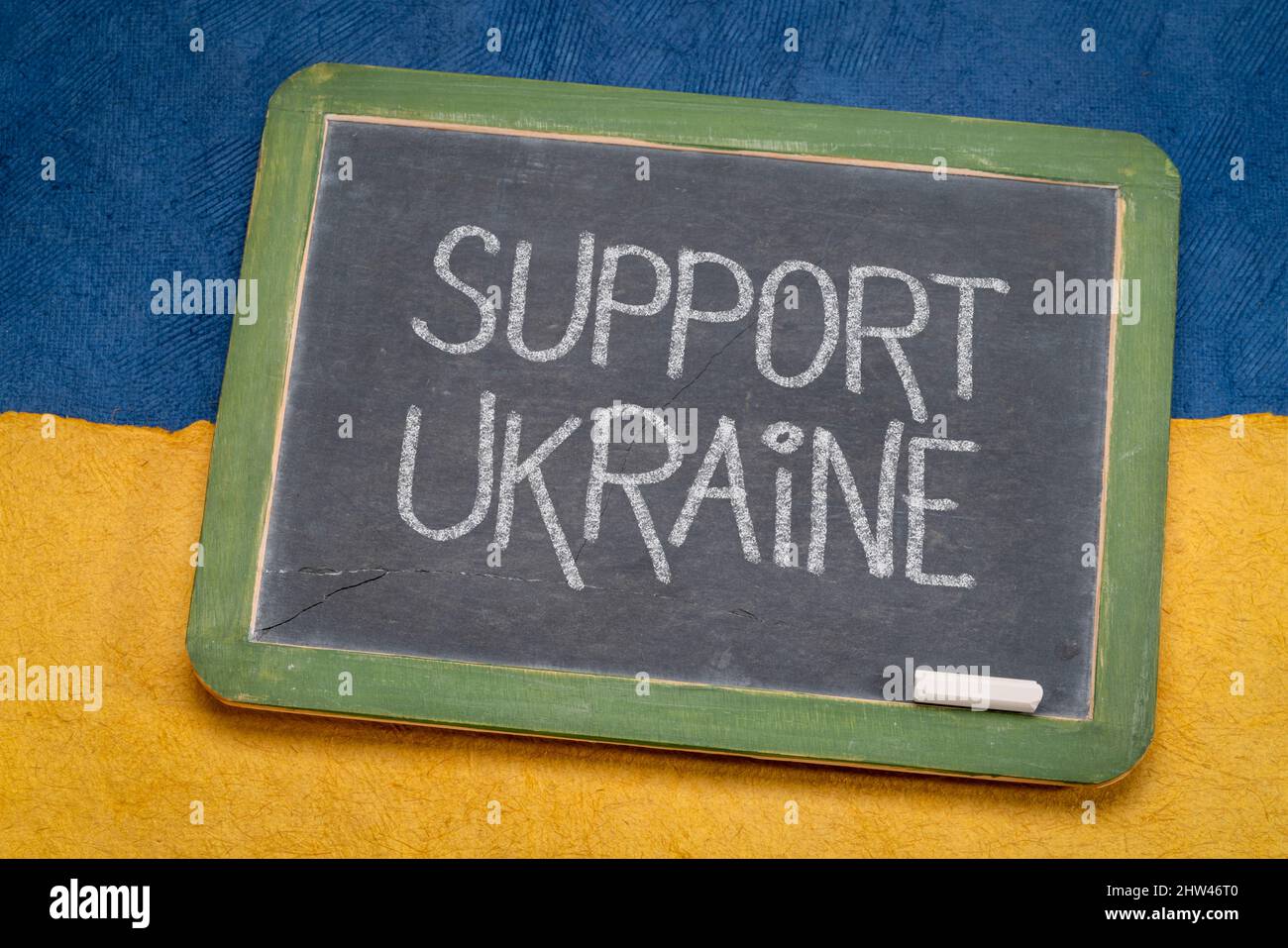 Sostenere l'Ucraina - scrivere gesso bianco su una lavagna retrò ardesia contro carta astratto a colori della bandiera nazionale Ucraina, blu e giallo Foto Stock
