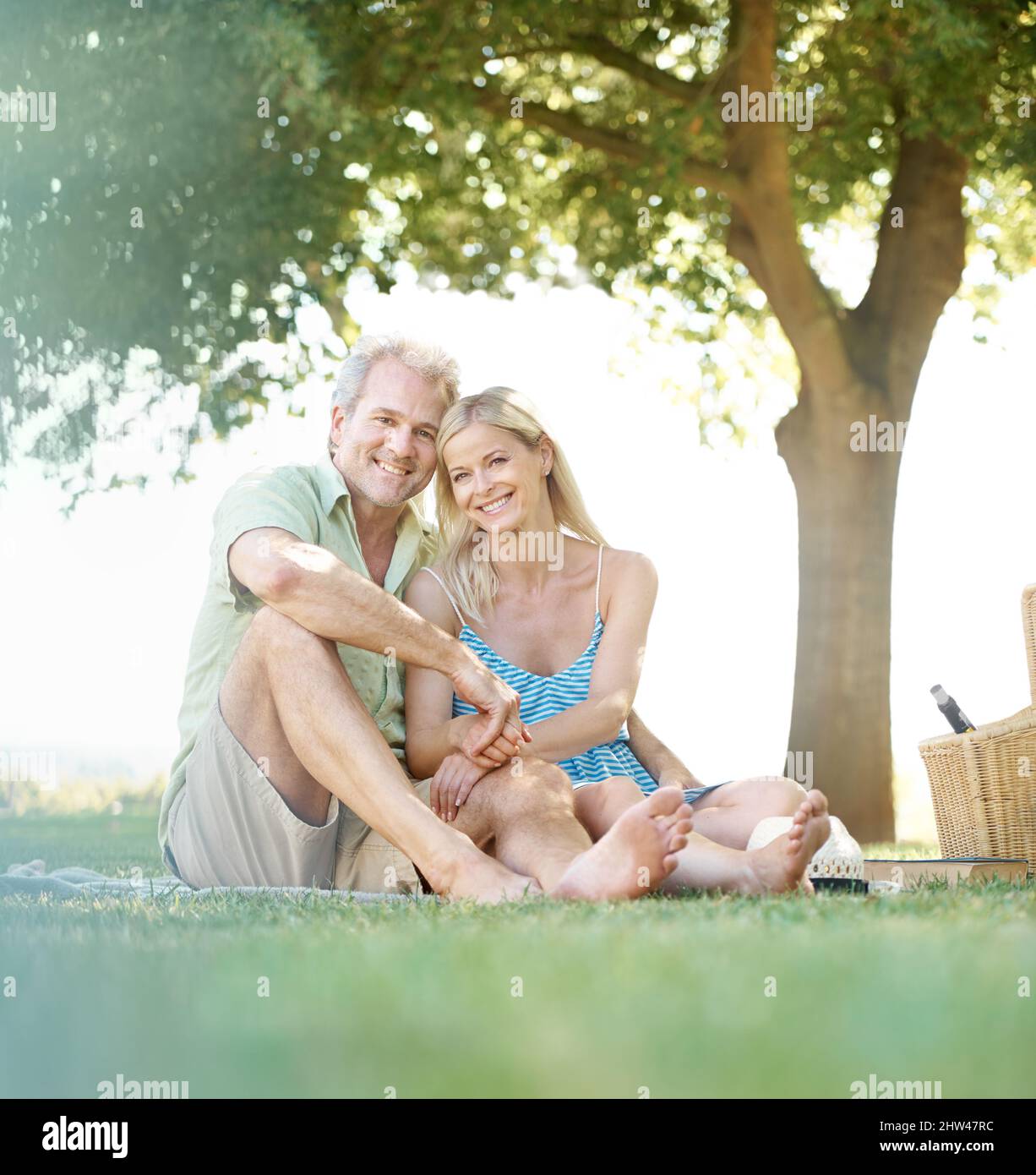 Pausa fine settimana. Un marito e una moglie felici sorridono alla macchina fotografica mentre si siedono in un parco per fare un picnic. Foto Stock