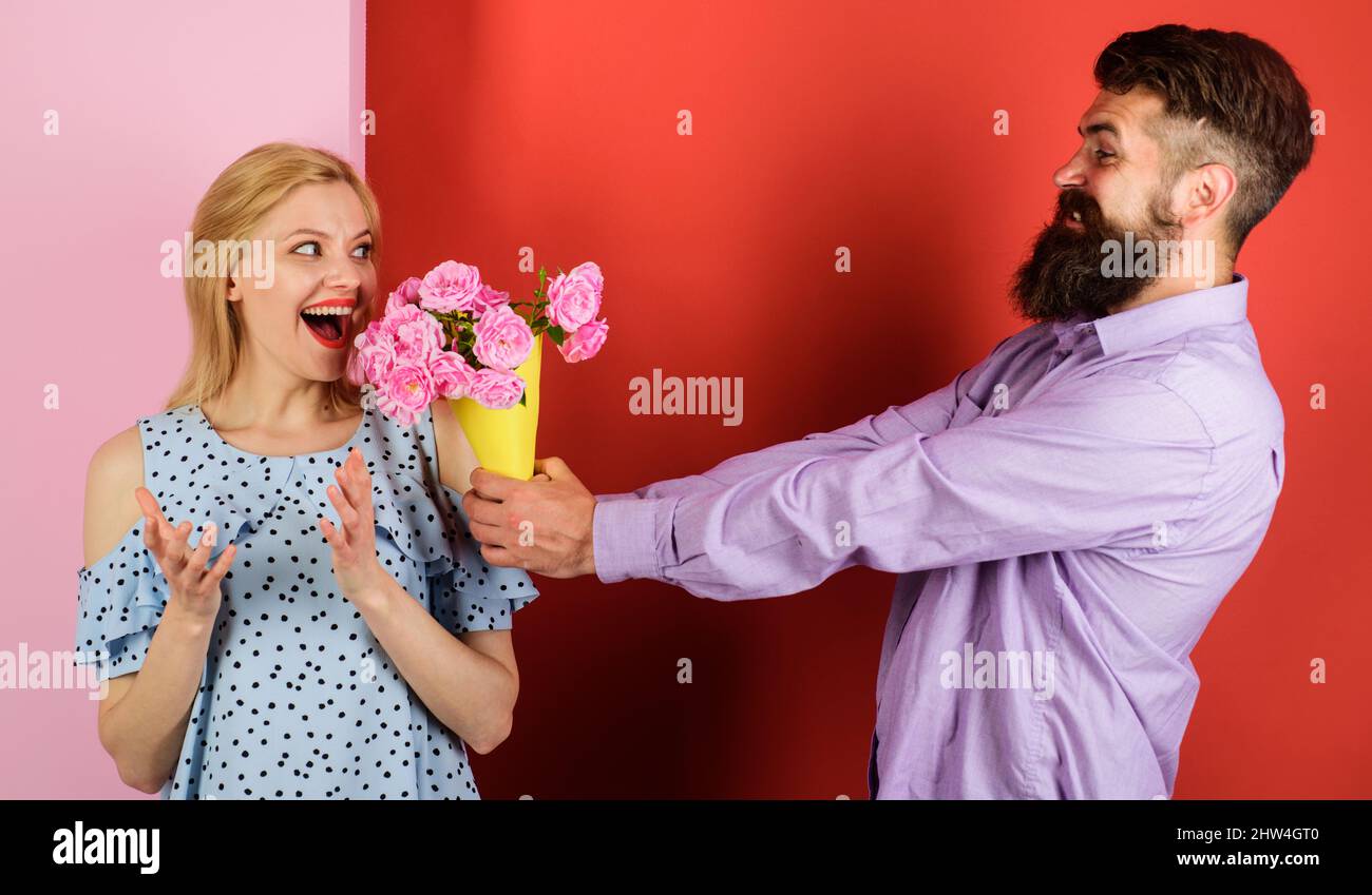 Coppia innamorata con bouquet di fiori. Bell'uomo barbuto dare rose alla donna. Amore, relazione. Foto Stock