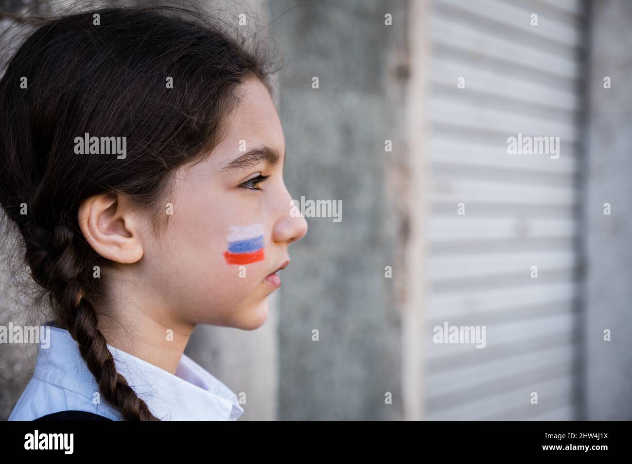 Ritratto di una bambina triste con colori russi sul viso. Concetto di pace e protezione per i bambini Foto Stock