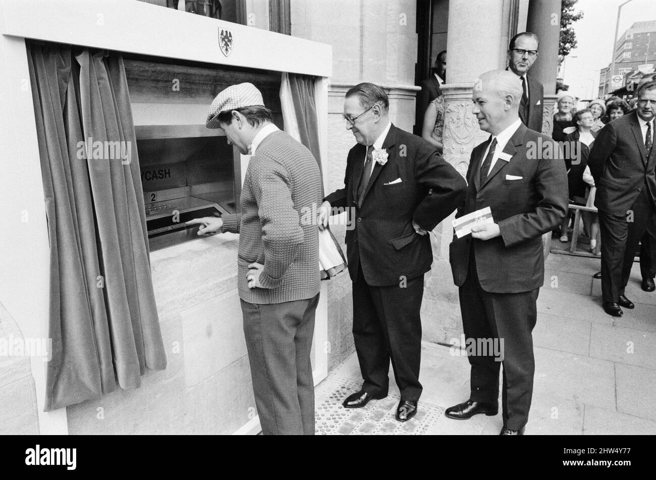 The Worlds First ATM, Cash Machine viene presentato alla Barclays Bank, a Enfield, Middlesex, appena a nord di Londra. 27th giugno 1967. L'immagine mostra l'attore Reg Varney nel suo cappuccio bianco. Barclays ATM, 27th giugno 1967. Sir Thomas Bland, vice presidente della Barclays Bank, rivela una cassa robot che eroga denaro in qualsiasi momento del giorno o della notte. Progettata e sviluppata in collaborazione con De la rue Instruments e con il Dipartimento dei servizi di gestione delle banche, la macchina BarclayCash è installata presso la filiale Enfield. Reg Varney, attore, ha preso il tempo dalle riprese per la serie televisiva "Beggar Your Neighbor" a Northwood To Foto Stock