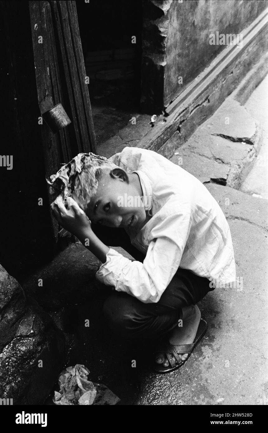 Vita nel 1960s coloniale Hong Kong, con una popolazione in rapida crescita di oltre 4 milioni di persone, molti sono costretti a vivere in baraccopoli e baraccopoli, nella foto di gennaio 1968. La nostra immagine mostra ... bambino lavaggio capelli sopra scarico. Foto Stock