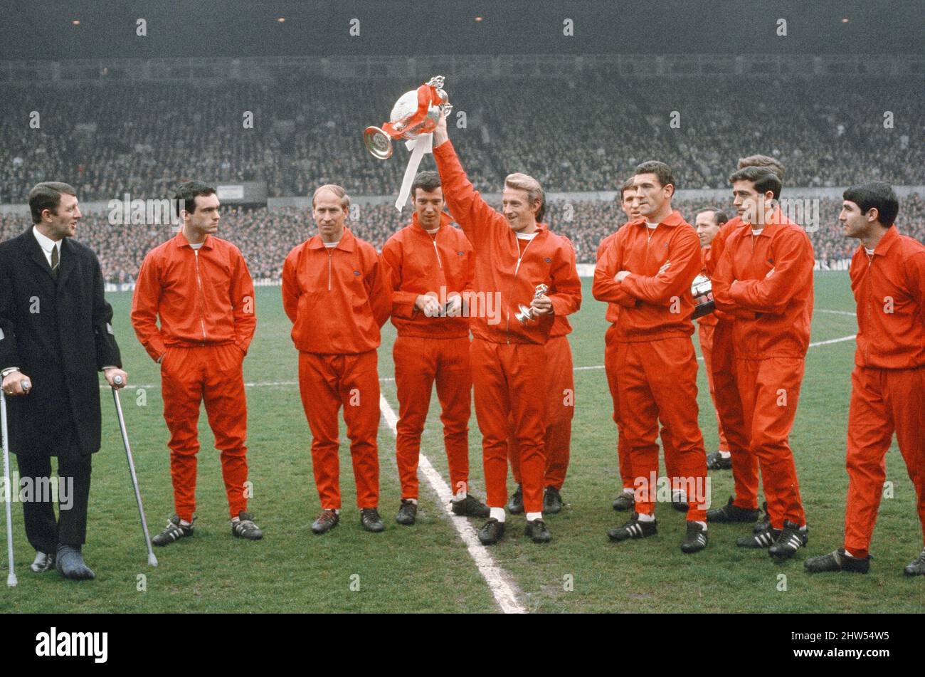 La stagione 1966-67 è stata la stagione 65th del Manchester United nella Football League, e la loro stagione 22nd consecutiva nella top divisione del calcio inglese. Hanno finito la stagione come campioni di campionato per la settima volta nella loro storia e il quinto sotto la gestione di Matt Busby, ma questo sarebbe il loro ultimo titolo di divisione superiore per 26 anni.(Picture shows) Dennis legge tenendo il trofeo aloft con i compagni di squadra. 13th maggio 1967 Foto Stock