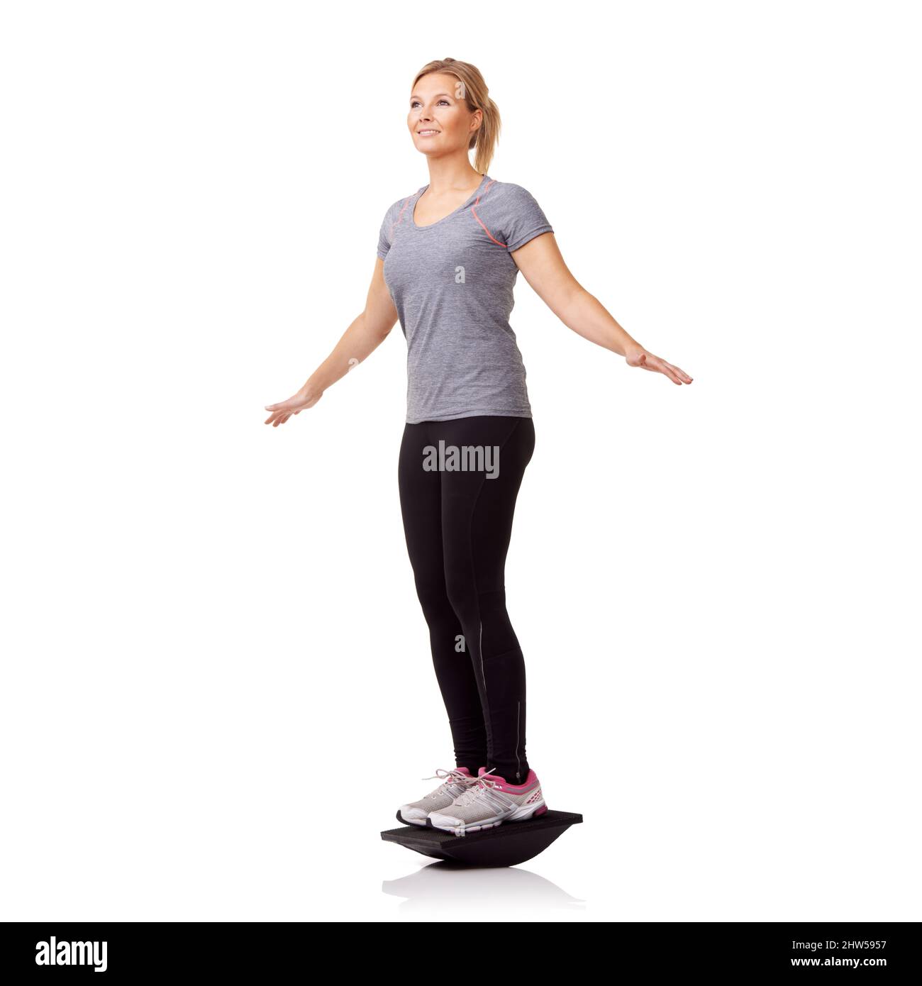 Provare una nuova forma di esercizio. Una donna piuttosto giovane che si esercita su un asse di equilibrio mentre isolato su uno sfondo bianco. Foto Stock