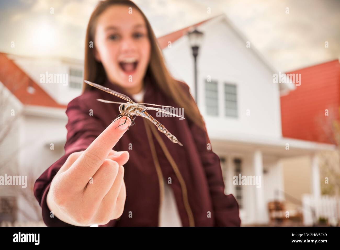 Ragazza sorridente (12-13) con libellula a dito Foto Stock