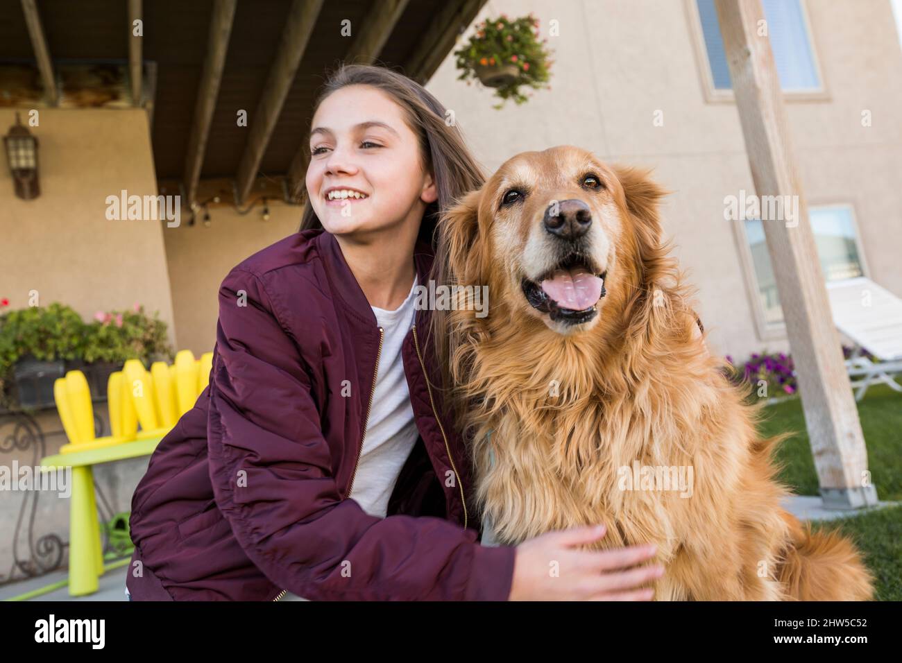 Ragazza (12-13) con Golden Retriever di fronte a casa Foto Stock