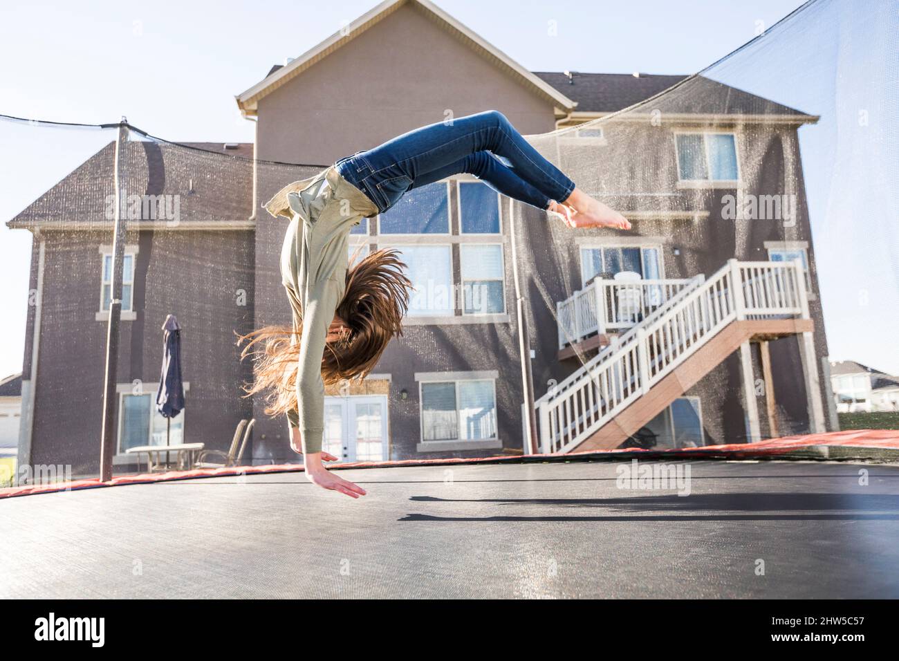 Ragazza (12-13) saltando sul trampolino di fronte a casa Foto Stock