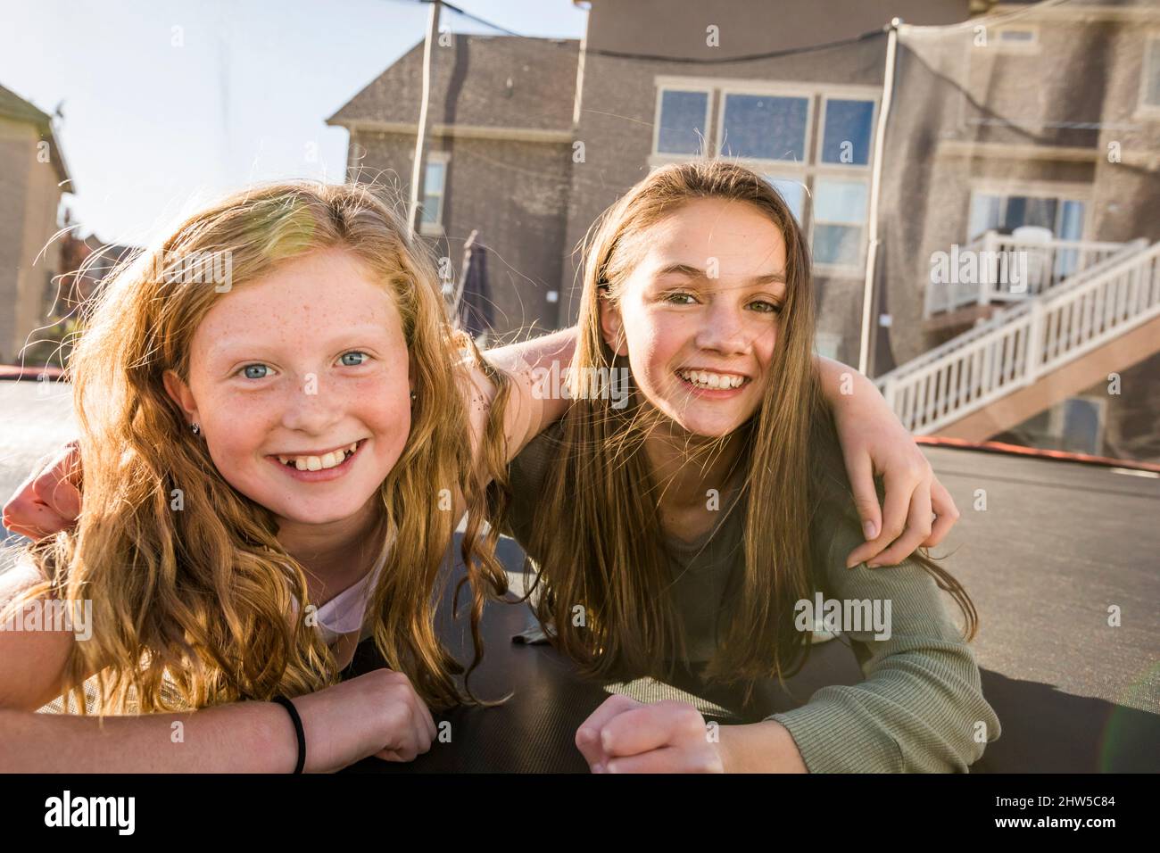 Ritratto di ragazze sorridenti (10-11, 12-13) sul trampolino di fronte a casa Foto Stock