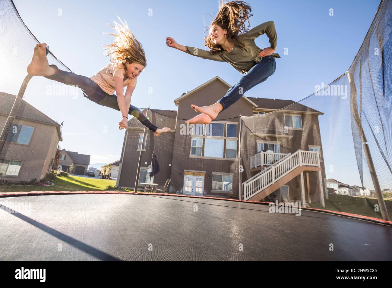 Ragazze (10-11, 12-13) che saltano sul trampolino di fronte a casa Foto Stock