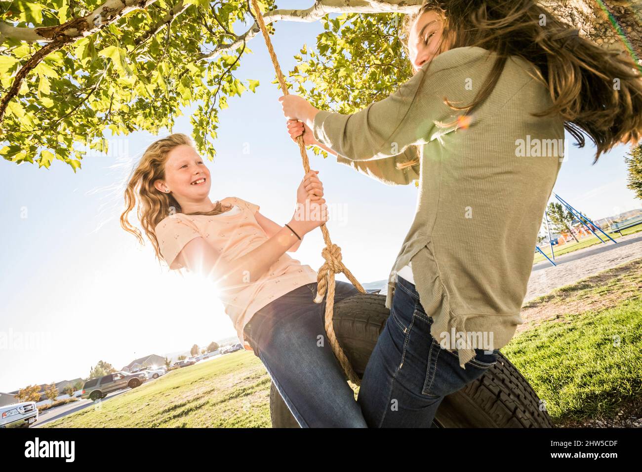 Ragazze sorridenti (10-11, 12-13) su pneumatico swing in giardino Foto Stock