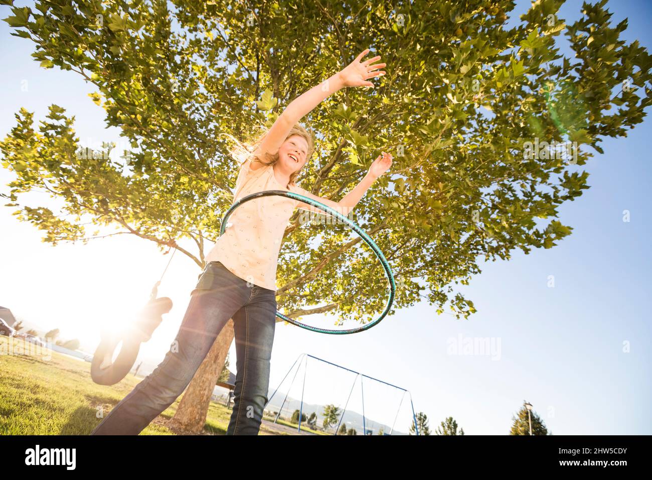 Ragazza (12-13) girando hula hoop, sorella (10-11) su pneumatico swing in background Foto Stock