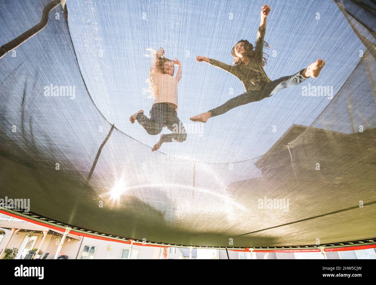 Vista ad angolo basso delle sorelle (10-11, 12-13) che saltano sul trampolino Foto Stock