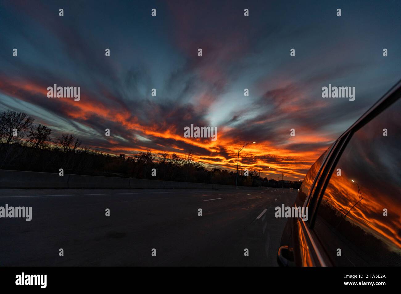 Stati Uniti, Idaho, Boise, Tramonto riflesso nella finestra laterale dell'auto che guida sulla superstrada Foto Stock