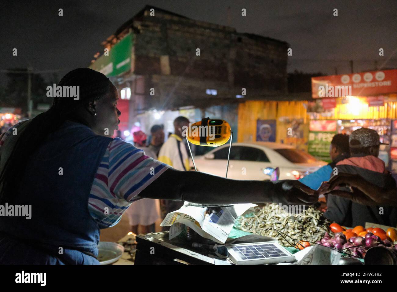 Un venditore di strada che utilizza una lampada solare fornendo al contempo servizi ai suoi clienti per le strade nelle baraccopoli di Kibera, Nairobi. Migliaia di famiglie in K. Foto Stock