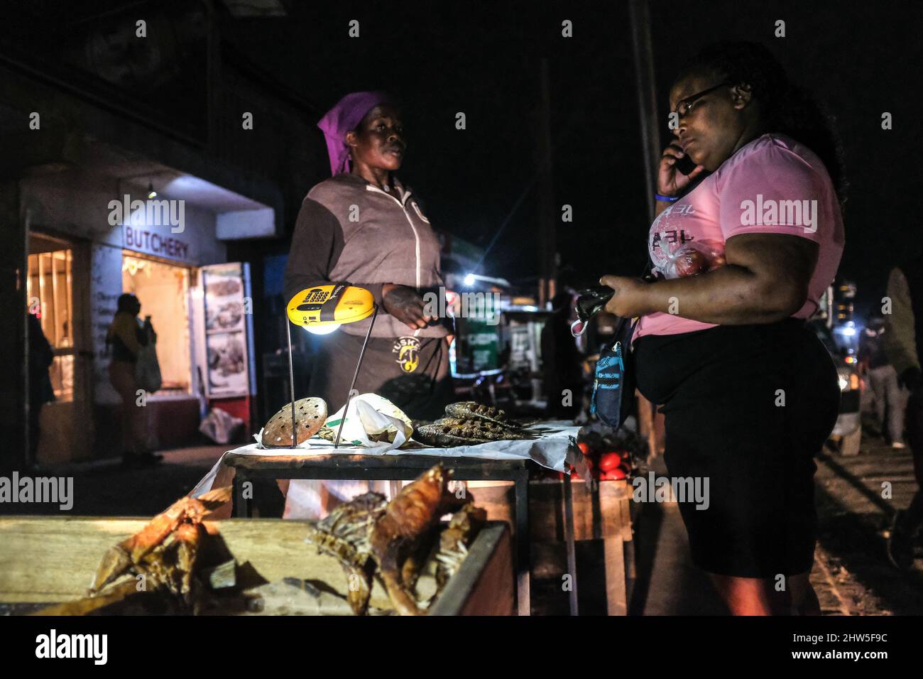 Un venditore di strada che utilizza una lampada solare fornendo al contempo servizi ai suoi clienti per le strade nelle baraccopoli di Kibera, Nairobi. Migliaia di famiglie in K. Foto Stock