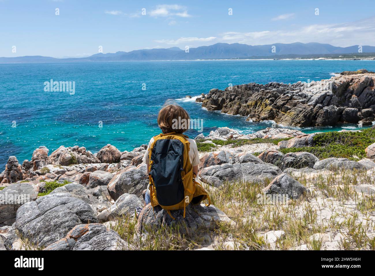 Sud Africa, De Kelders, Boy (8-9) guardando la costa dell'Oceano Atlantico Foto Stock