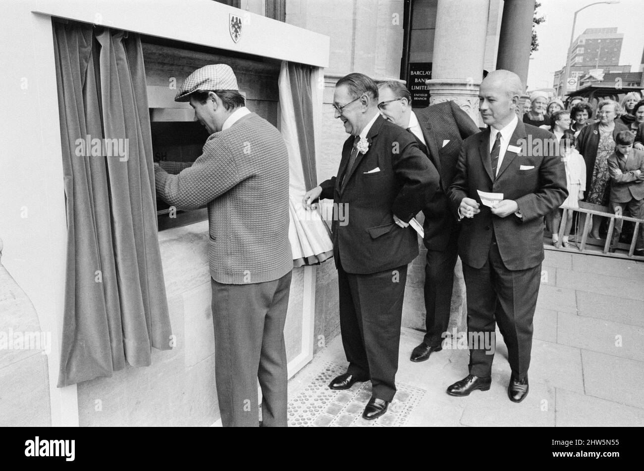 The Worlds First ATM, Cash Machine viene presentato alla Barclays Bank, a Enfield, Middlesex, appena a nord di Londra. 27th giugno 1967. L'immagine mostra l'attore Reg Varney nel suo cappuccio bianco. Barclays ATM, 27th giugno 1967. Sir Thomas Bland, vice presidente della Barclays Bank, rivela una cassa robot che eroga denaro in qualsiasi momento del giorno o della notte. Progettata e sviluppata in collaborazione con De la rue Instruments e con il Dipartimento dei servizi di gestione delle banche, la macchina BarclayCash è installata presso la filiale Enfield. Reg Varney, attore, ha preso il tempo dalle riprese per la serie televisiva "Beggar Your Neighbor" a Northwood To Foto Stock