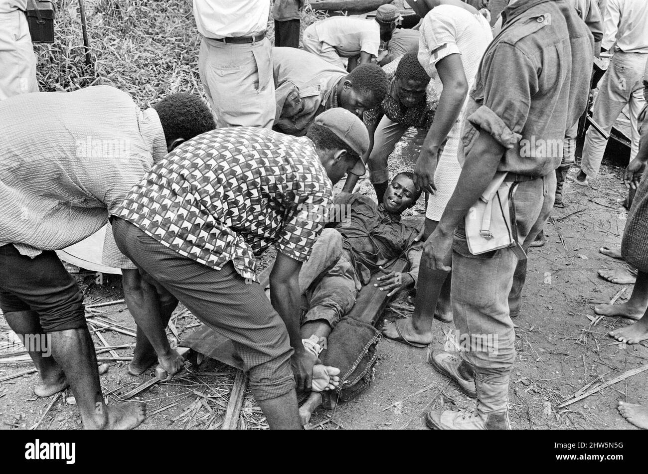 I soldati e gli assistenti di Biafran hanno visto qui portare un compagno ferito su una barella durante il conflitto di Biafra. 11th giugno 1968. La guerra civile nigeriana, nota anche come guerra di Biafran, è durata due anni e mezzo, dal 6 luglio 1967 al 15 gennaio 1970, ed è stata combattuta per contrastare la secessione di Biafra dalla Nigeria. Il popolo indigeno Igbo di Biafra sentì di non poter più coesistere con il governo federale dominato dal nord a seguito dell'indipendenza dalla Gran Bretagna. Le tensioni politiche, economiche, etniche, culturali e religiose si sono infine follate nella guerra civile dopo i 1966 mili Foto Stock