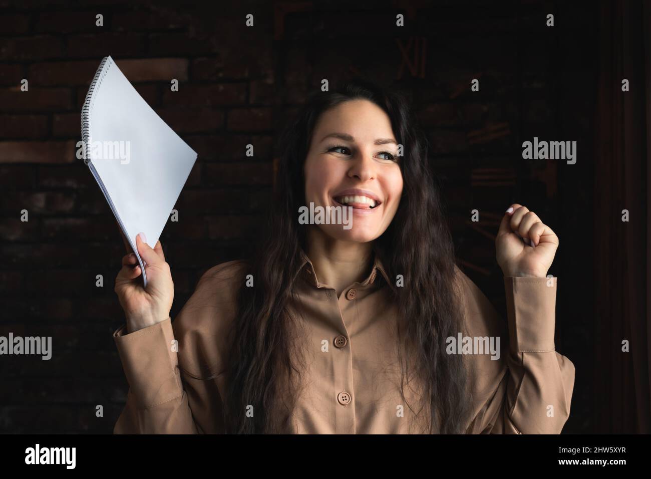 Una donna bruna attraente con documenti. Vista frontale. Foto verticale. Spazio di copia. Posiziona per testo. Concetto di gioia di successo. Foto Stock