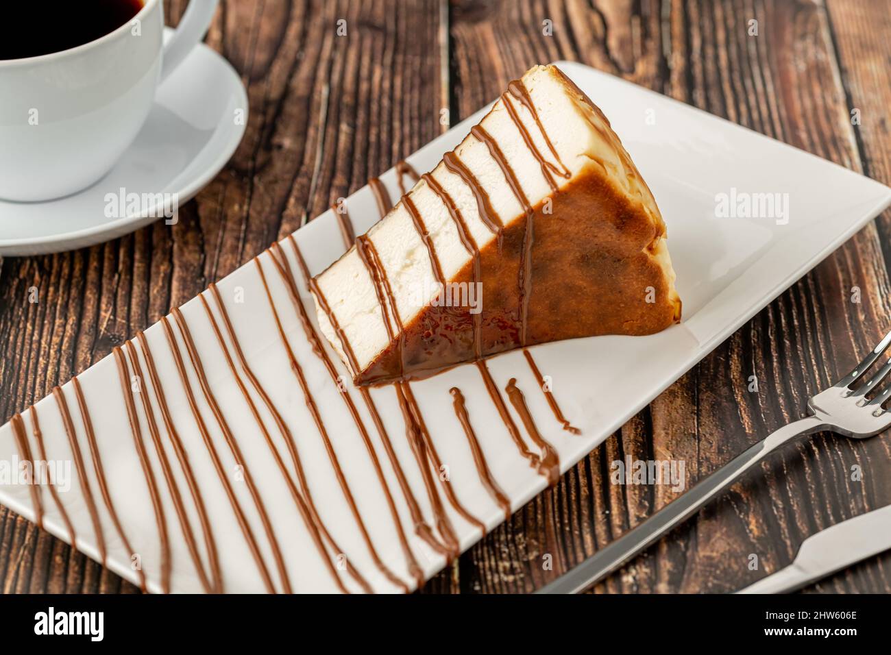 Cheesecake a fette di san sebastian con caffè su tavola di legno Foto Stock