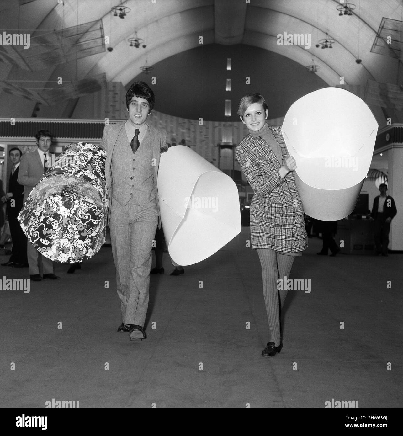 Twiggy con il suo manager, Justin de Villeneuve che porta alcune delle sedie di carta alla mostra Ideal Home. 6th marzo 1967. Foto Stock