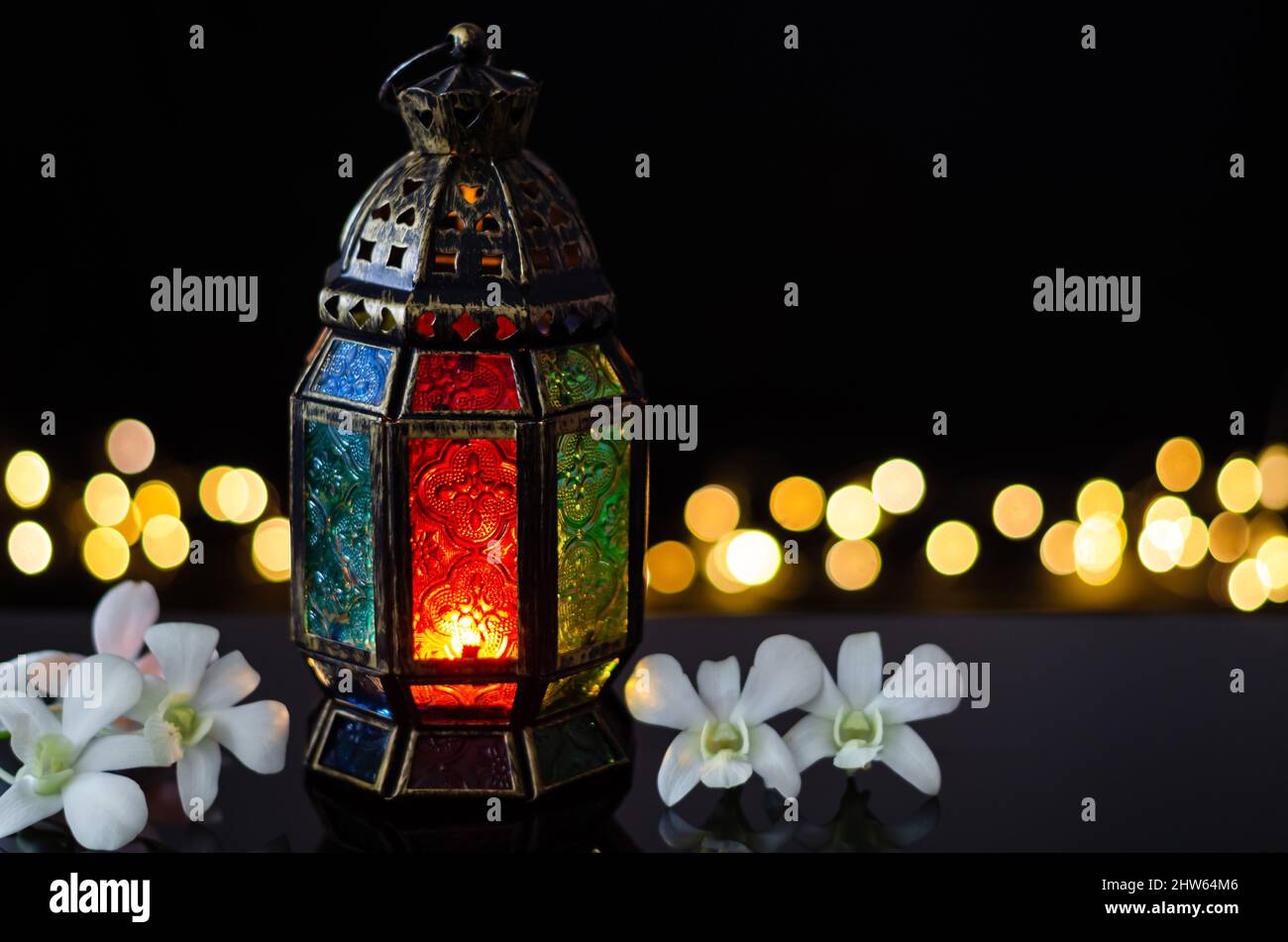 Lanterna con fiore bianco orchidea su sfondo bokeh chiaro per la festa musulmana del mese santo di Ramadan Kareem. Foto Stock