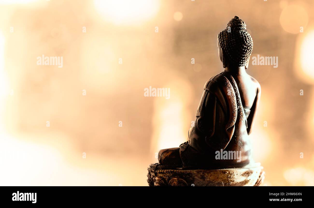 Lato posteriore della statua del Buddha meditante. Sfondo bokeh. Colori caldi. Concetto di tranquillità Foto Stock