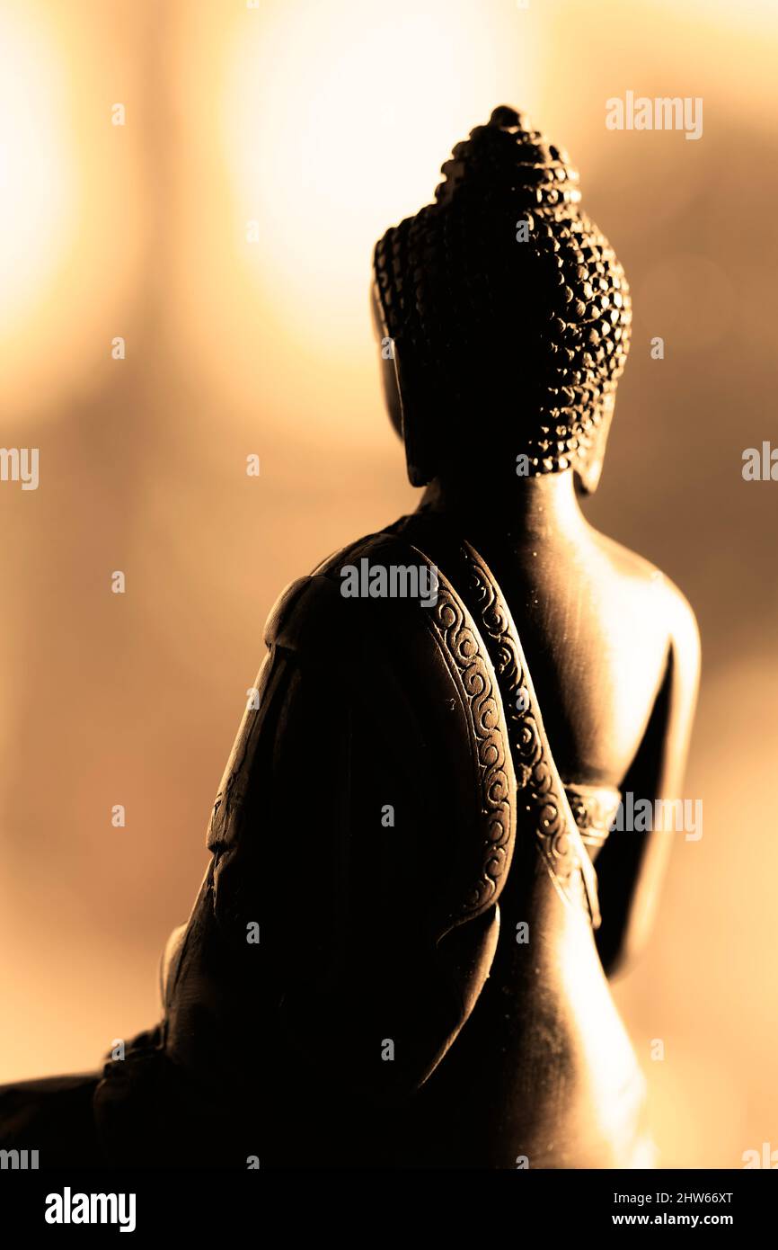 Lato posteriore della statua del Buddha meditante. Sfondo bokeh. Colori caldi. Concetto di tranquillità Foto Stock
