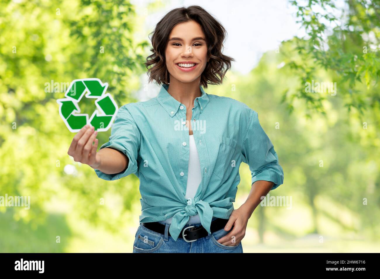 giovane donna sorridente che tiene il cartello verde di riciclaggio Foto Stock