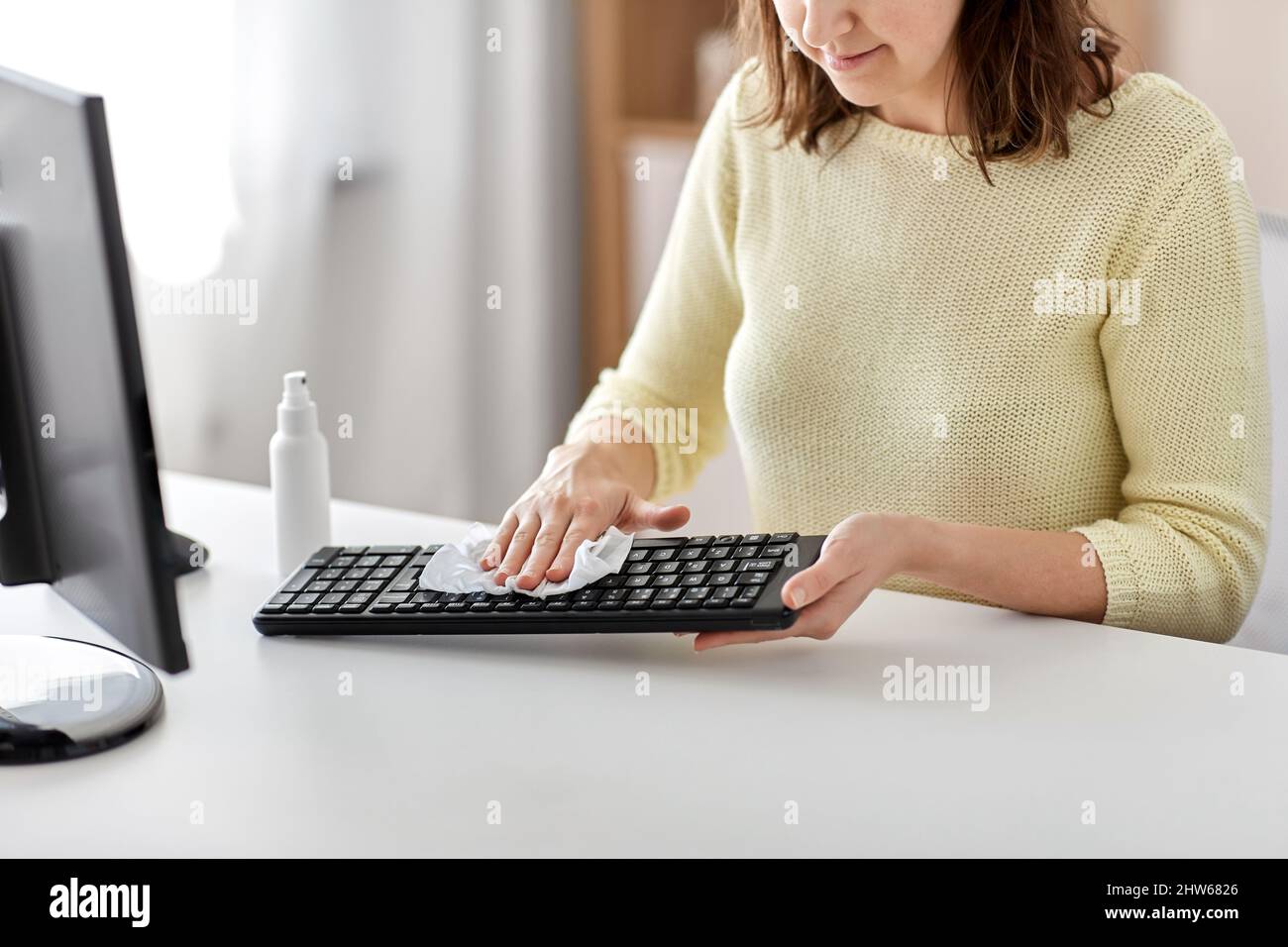 primo piano della donna che pulisce la tastiera con igienizzatore Foto Stock