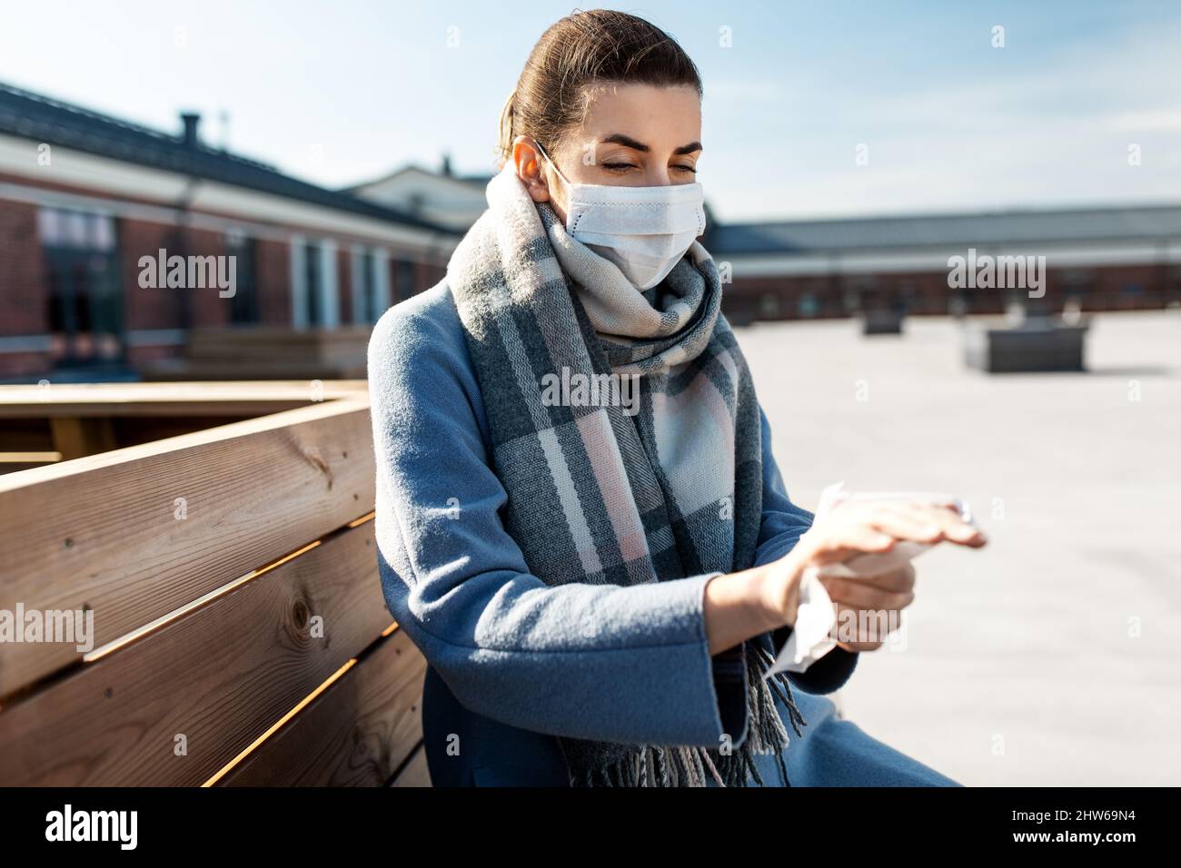 donna in maschera pulizia mani con salvietta bagnata in città Foto Stock