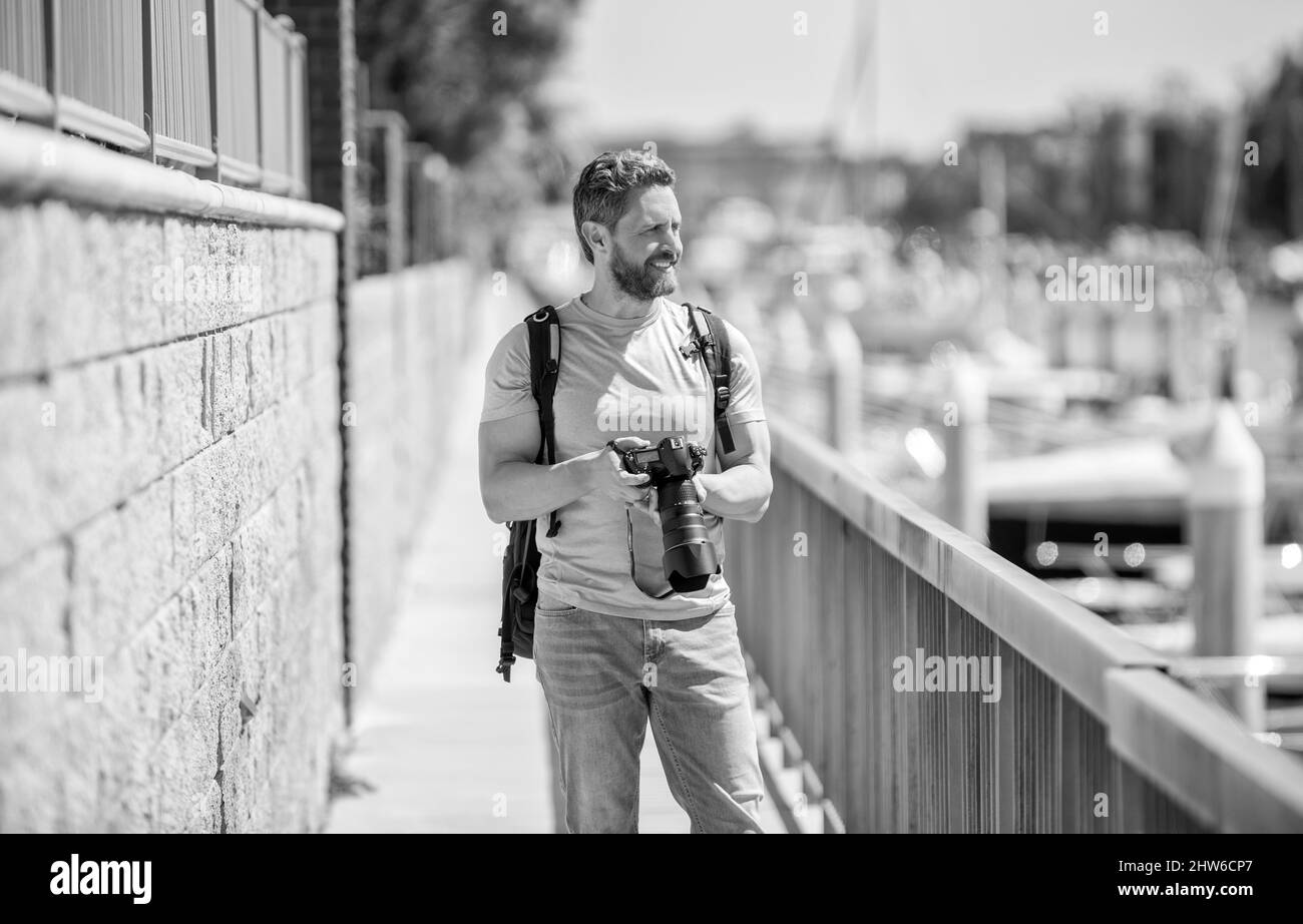 Uomo tenere la macchina fotografica in piedi sulla passeggiata. Fotografia di vacanza. Fotografia di viaggio Foto Stock