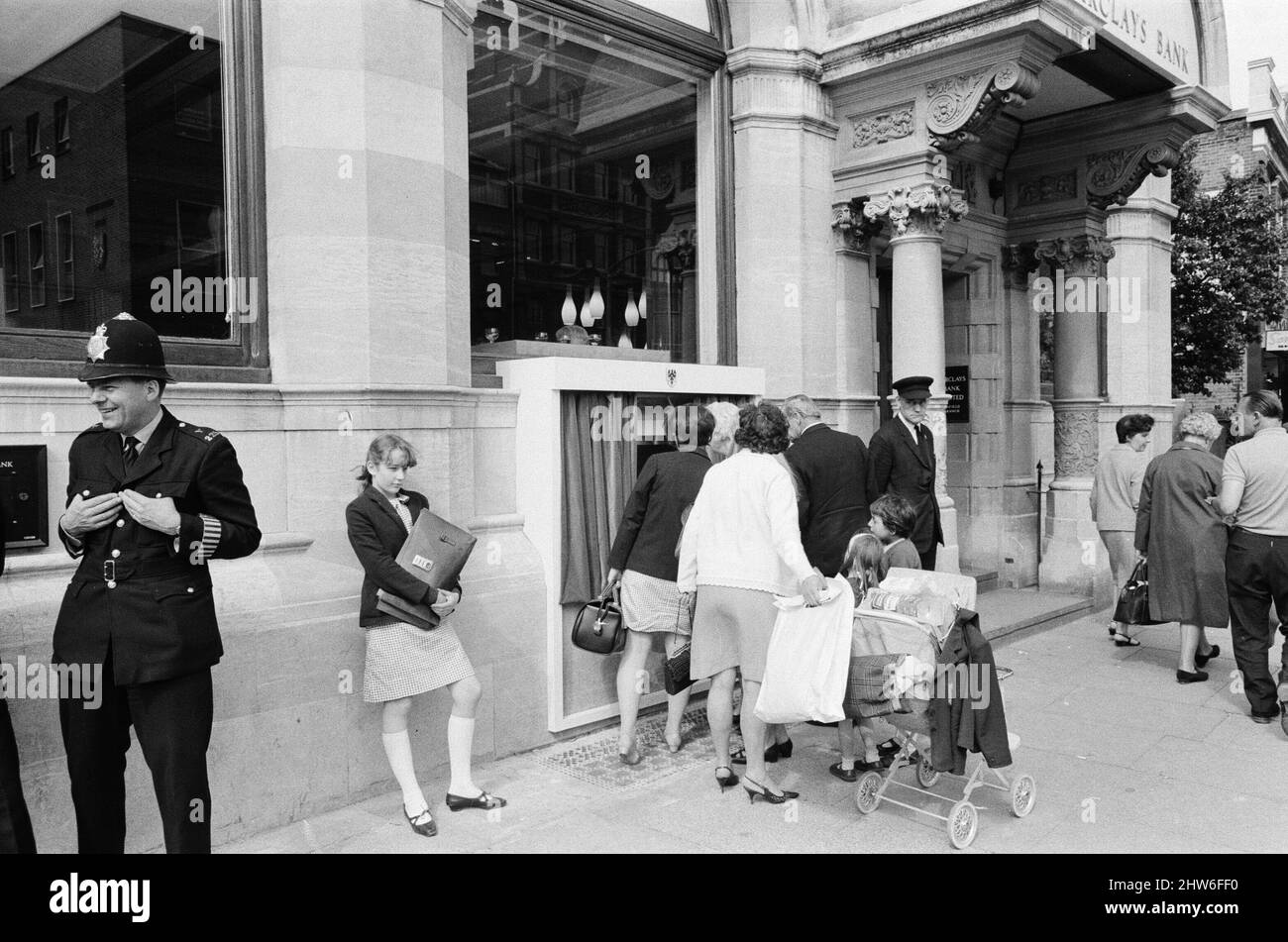 The Worlds First ATM, Cash Machine viene presentato alla Barclays Bank, a Enfield, Middlesex, appena a nord di Londra. 27th giugno 1967. L'immagine mostra la folla di acquirenti locali e spettatori, vedendo il primo ATM al mondo lavoro per la prima volta. Barclays ATM, 27th giugno 1967. Sir Thomas Bland, vice presidente della Barclays Bank, rivela una cassa robot che eroga denaro in qualsiasi momento del giorno o della notte. Progettata e sviluppata in collaborazione con De la rue Instruments e con il Dipartimento dei servizi di gestione delle banche, la macchina BarclayCash è installata presso la filiale Enfield. Attore, Reg Varney ha preso tempo fuori da filmi Foto Stock
