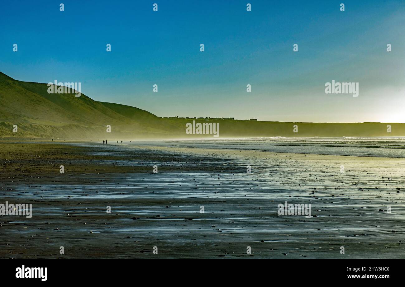 Guardando indietro lungo Rhossili Beach verso Rhossili con sabbia bagnata in un giorno di gennaio al sole Foto Stock