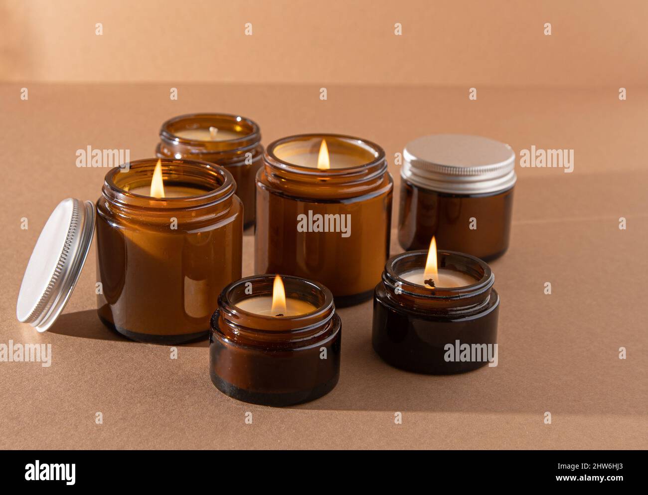Un set di candele aromatiche diverse in vasetti di vetro marrone. Candela  profumata fatta a mano. Le candele di soia stanno bruciando in un vaso.  Aromaterapia e relax in spa e casa