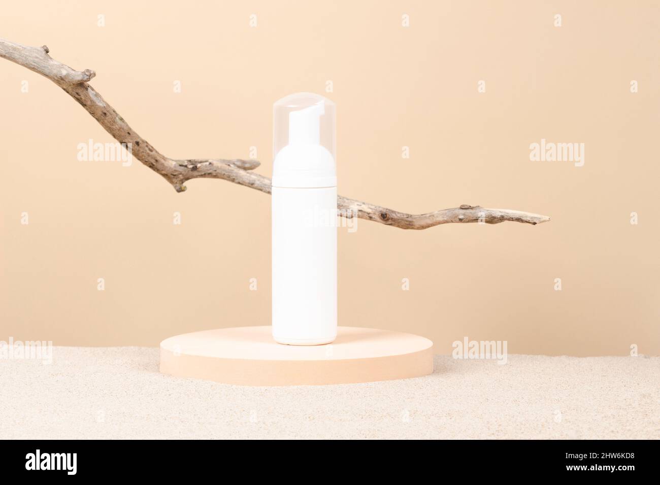 Confezione bianca in plastica bianca pompa cosmetica bottiglia per crema mousse su piattaforma tonda da podio con sabbia da spiaggia e sfondo beige. Anteriore Foto Stock