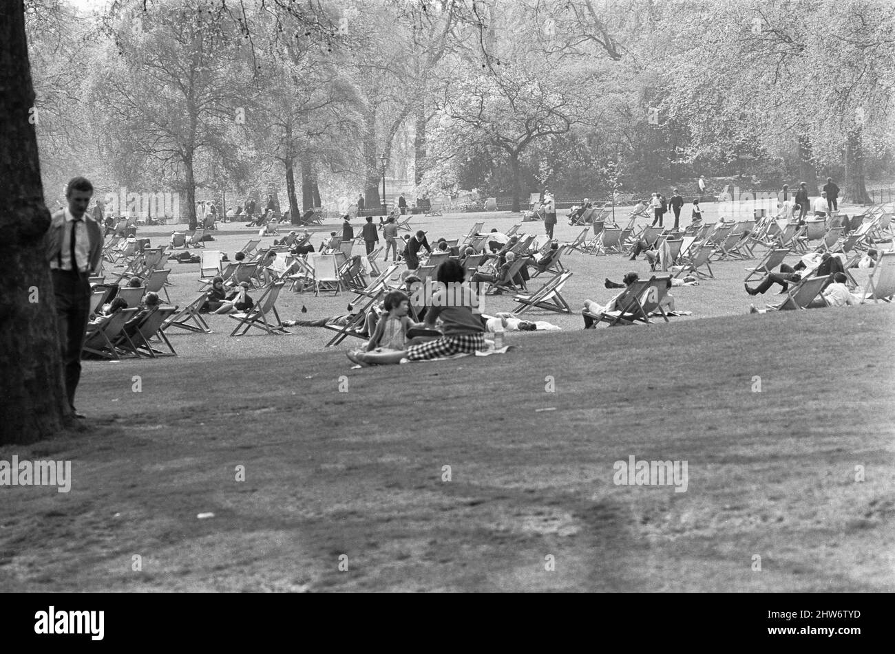 Gli impiegati e le giovani famiglie apprezzano il calore e il sole primaverile nel St James Park. 26th aprile 1968 Foto Stock