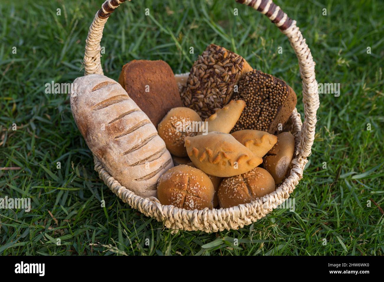 Assorti di gustoso pane fresco e bianco fatto in casa con i semi in cesto di vimini in piedi sul verde erba. Foto di alta qualità Foto Stock