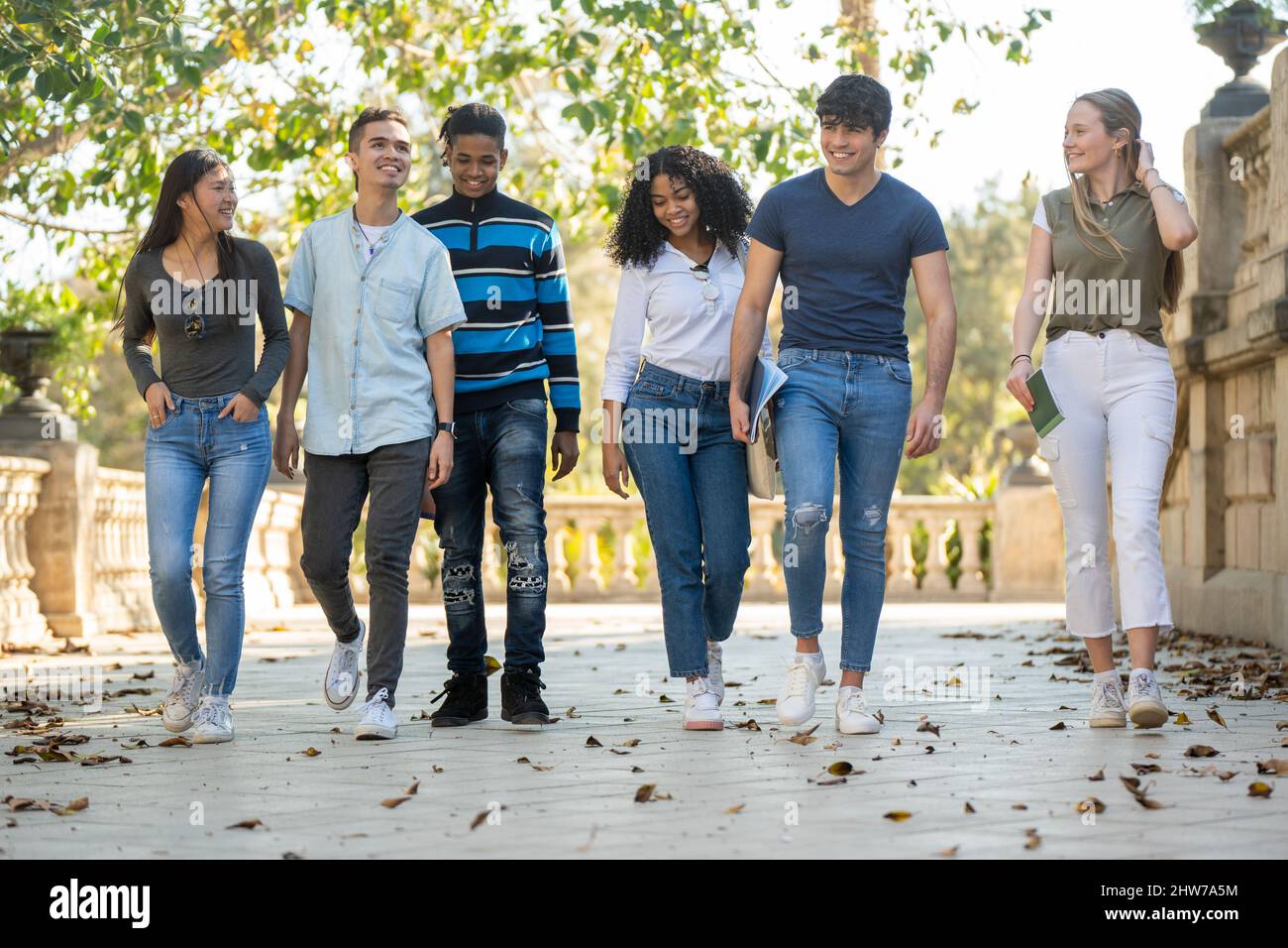 Una fila di giovani gruppi di studenti multirazziali che camminano insieme all'aperto Foto Stock