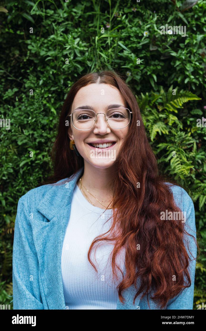 Ritratto di donna sorridente con lunghi capelli rossi che tirano la mano verso la fotocamera. Ritratto di bellezza di donna naturale divertirsi Foto Stock