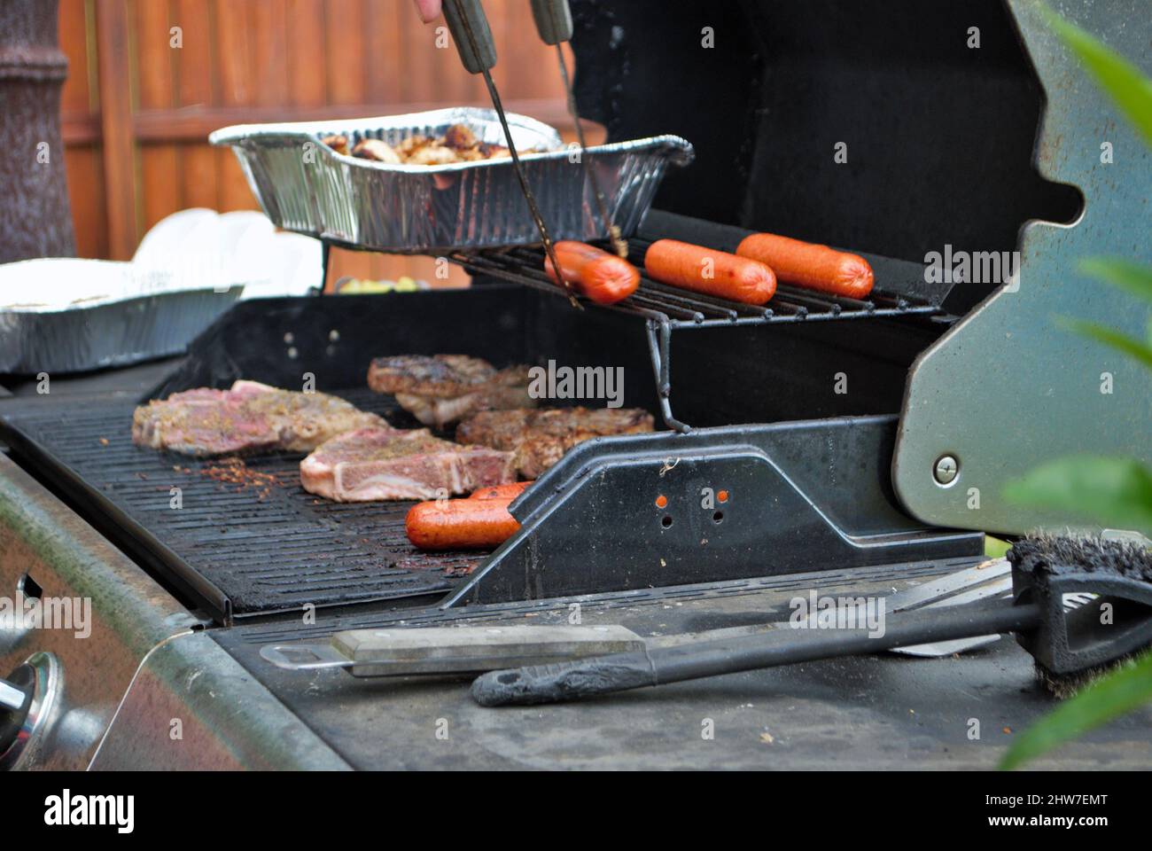 Hot dog e bistecca sulla griglia in un cortile di cucina Foto Stock