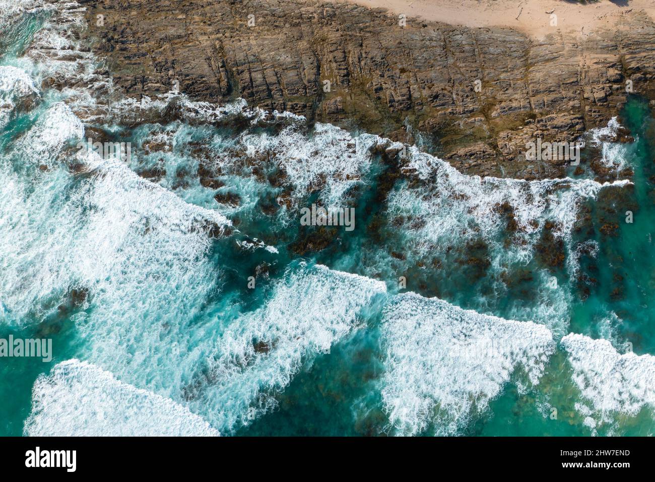 Vista aerea dall'alto verso il basso delle onde oceaniche che si infrangono su una costa rocciosa lungo la Great Ocean Road in Australia Foto Stock
