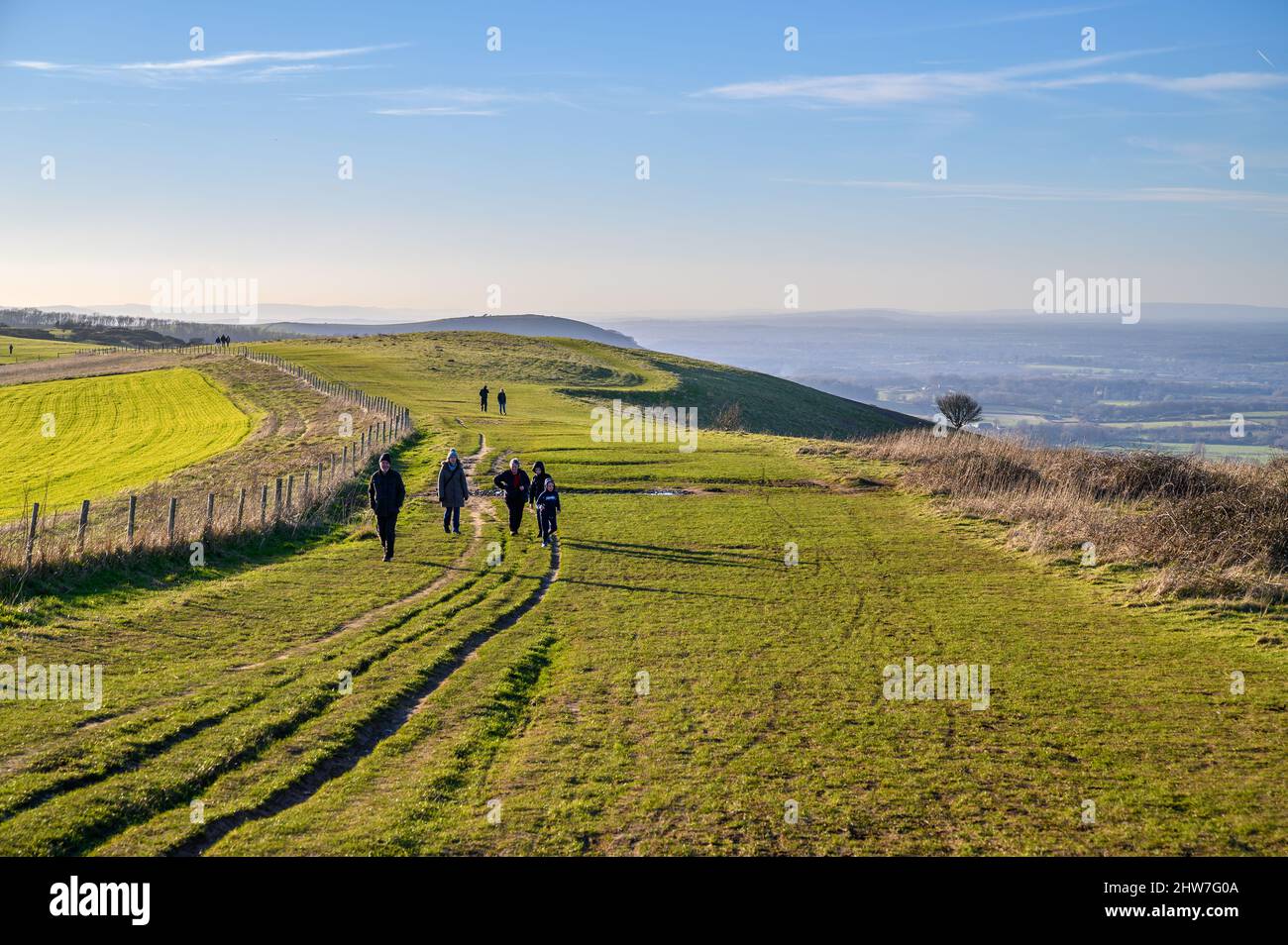 Viste di grande portata sul paesaggio del Sussex nel sole di febbraio con la gente che cammina su South Downs Way vicino a Ditchling Beacon nel Sussex orientale, Inghilterra. Foto Stock
