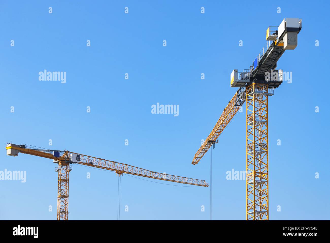 Due gru gialle su un cantiere contro il cielo blu, spazio copia, fuoco selezionato, profondità di campo stretta Foto Stock