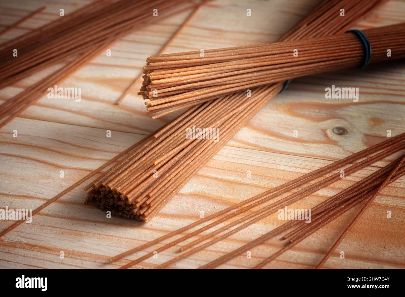 Spaghetti integrali, pasta sana alternativa dal grano duro intero su un tavolo di legno chiaro, spazio copia, fuoco selezionato, profondità di campo ristretta Foto Stock
