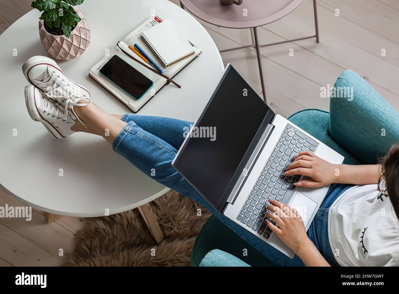 Giovane donna che usa lo schermo del laptop vuoto, mock-up, lavoro a casa, vista dall'alto Foto Stock