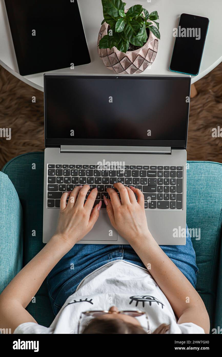 Giovane donna che usa lo schermo del laptop vuoto, mock-up, lavoro a casa, vista dall'alto Foto Stock