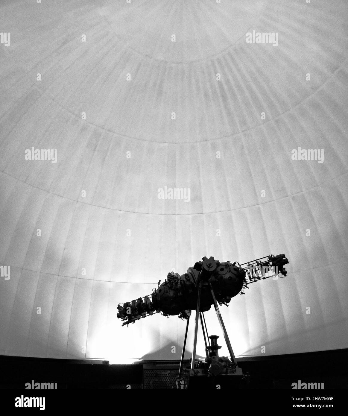 Scala di grigi di un grande telescopio all'interno di un edificio bianco di forma rotonda Foto Stock