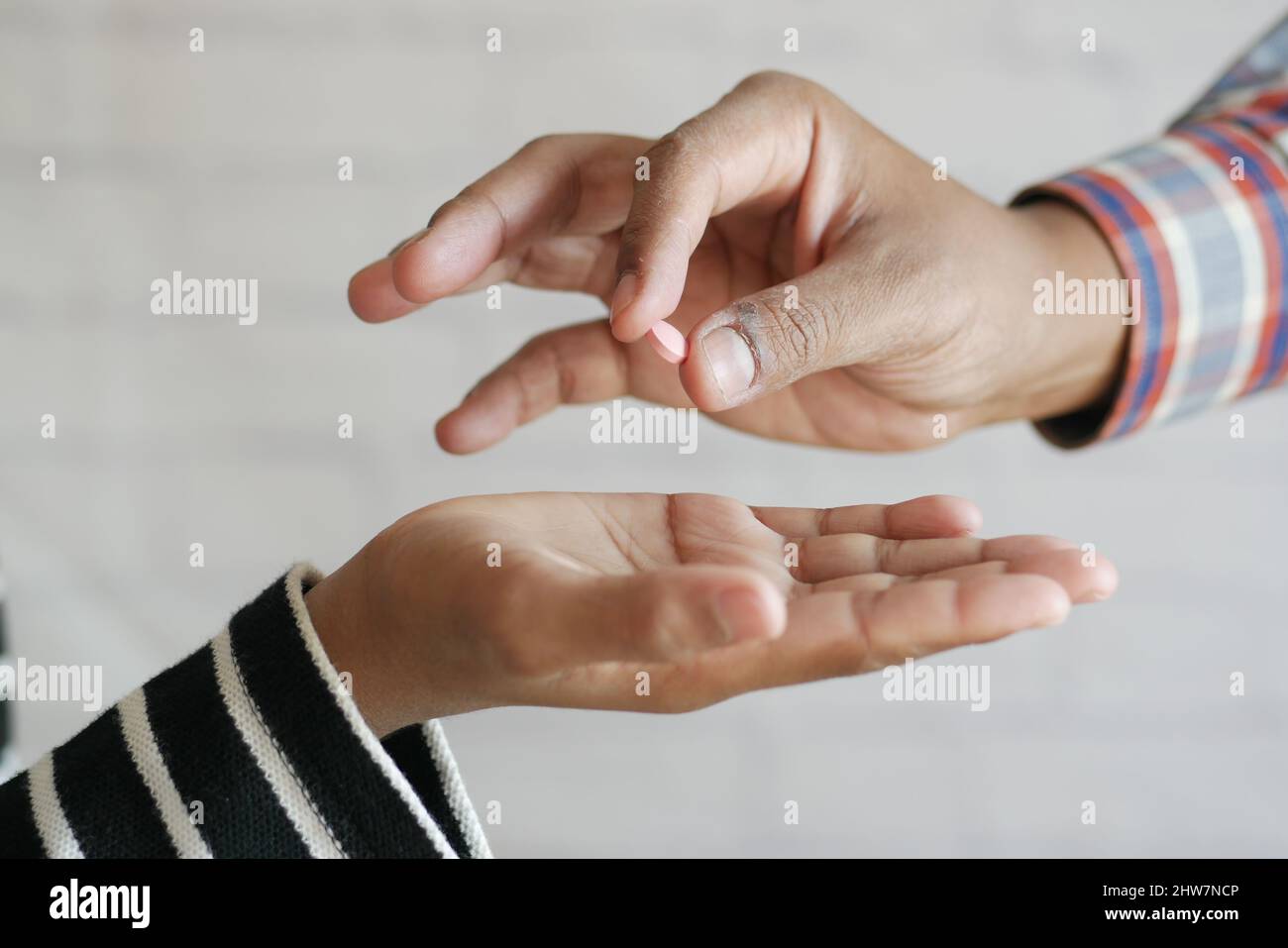 Primo piano di mano uomo tenere pillole e dare ad altra persona Foto Stock